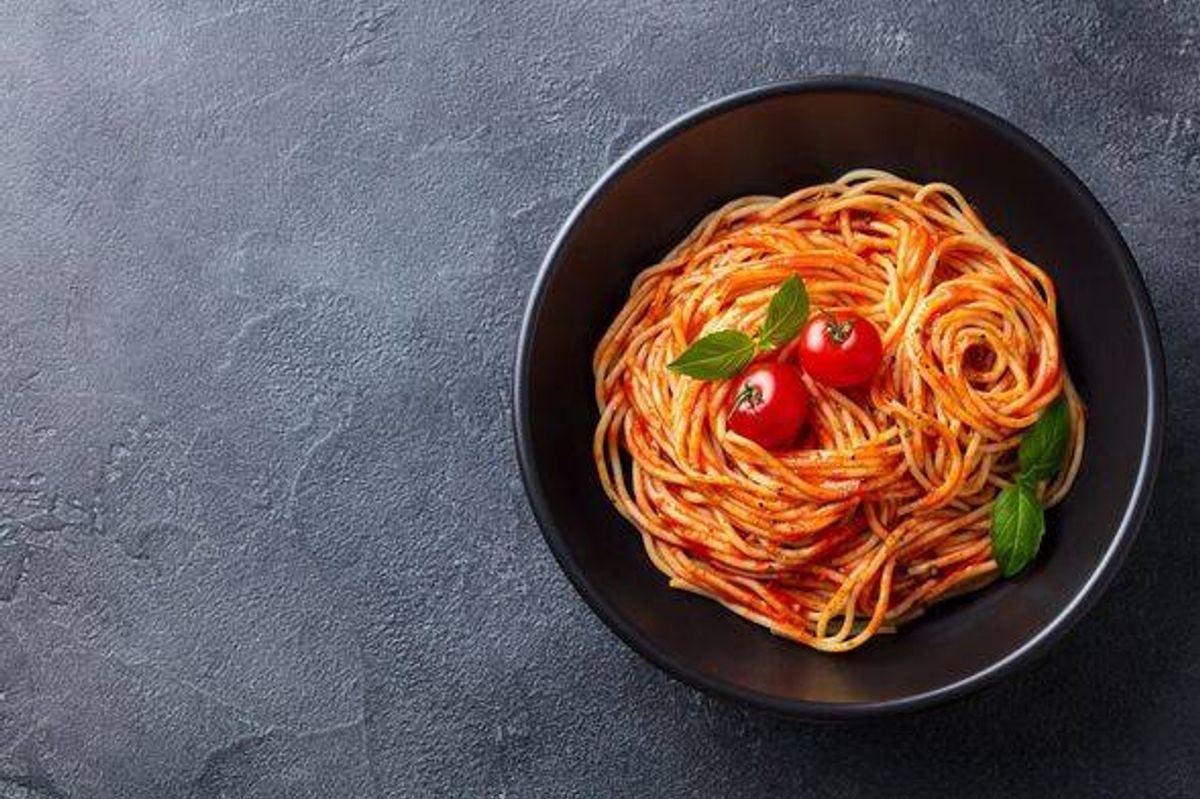 Pasta, spaghetti ជាមួយទឹកជ្រលក់ប៉េងប៉ោះនៅក្នុងចានខ្មៅ
