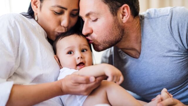 1780746894_2_Affectionate-young-couple-kissing-a-baby-at-home.jpg