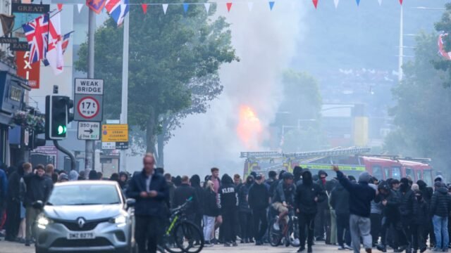 1781049360_Un-bus-en-feu-est-visible-alors-que-des-manifestants-se-rassemblent-sur-la-route-de-Newtownards-dans.jpeg