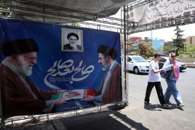 1781255935_2460275-des-iraniens-passent-devant-une-affiche-representa.jpg