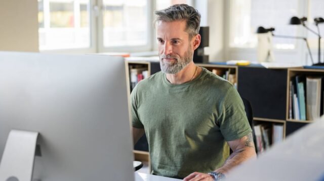 1_Focused-mature-male-professional-working-on-a-large-computer-screen-in-a-bright-office.jpg