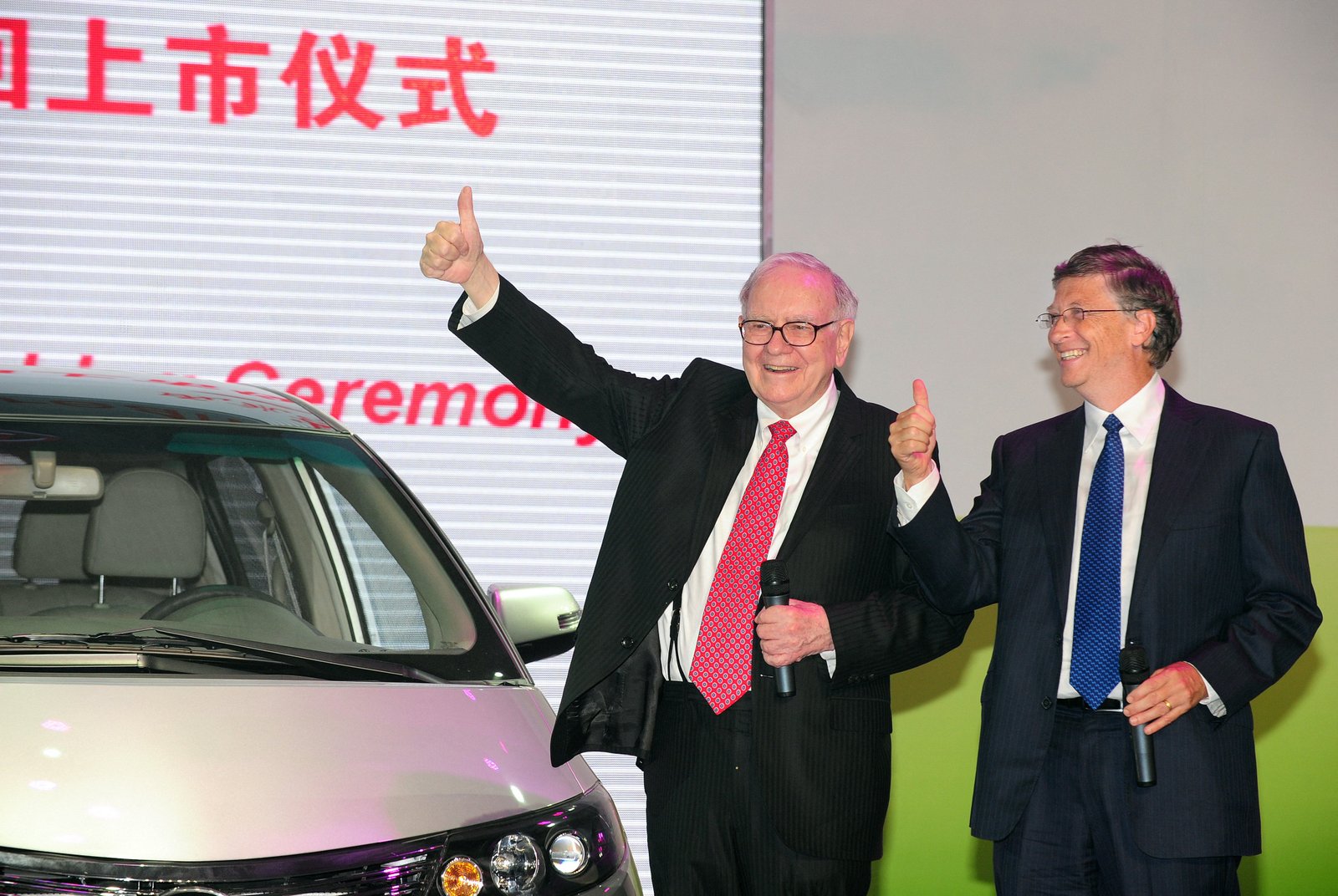 Warren Buffett (ឆ្វេង) និង Bill Gates (រូប) កាយវិការក្នុងពិធីសម្ពោធរថយន្តអគ្គិសនីទូទាំងប្រទេស BYD M6 របស់ប្រទេសចិន នៅថ្ងៃទី 29 ខែកញ្ញា ឆ្នាំ 2010 នៅទីក្រុងប៉េកាំង។