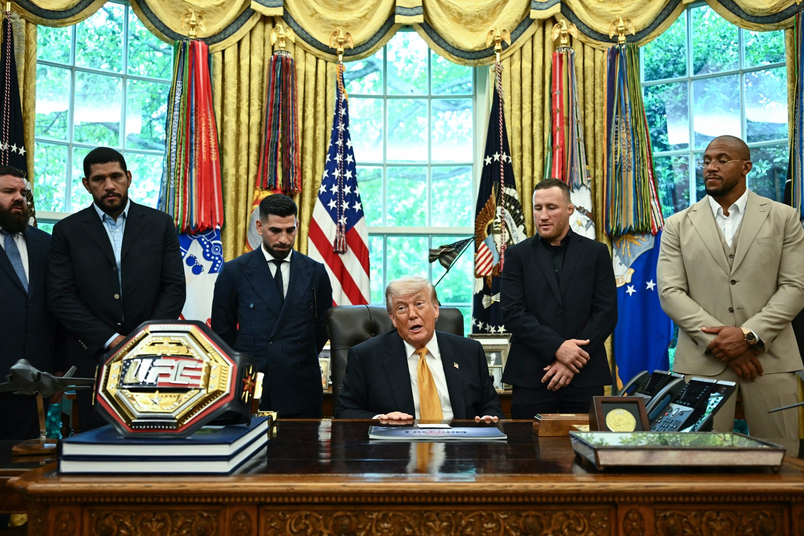 លោកប្រធានាធិបតី Donald Trump និយាយអំពីព្រឹត្តិការណ៍នាពេលខាងមុខ រួមជាមួយ (l/r) គ្រូបង្ហាត់ក្បាច់គុនចម្រុះអាមេរិក Plinio Cruz, សិល្បករក្បាច់គុនចម្រុះប្រេស៊ីល Alex Pereira, វិចិត្រករក្បាច់គុនចម្រុះ Georgian-Spanish Ilia Topuria, សិល្បករក្បាច់គុនចម្រុះអាមេរិក Justin Gaethje និងសិល្បករក្បាច់គុនចម្រុះបារាំង Ciryl Gane