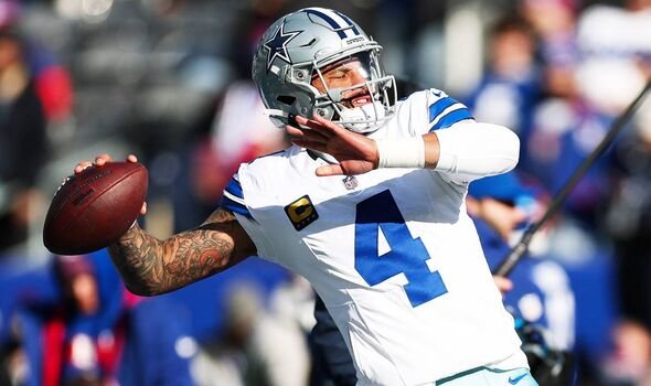 អ្នកលេង NFL នៅក្នុងឧបករណ៍ពណ៌ស និងពណ៌ខៀវ ជាមួយនឹងបាល់ទាត់អាមេរិក