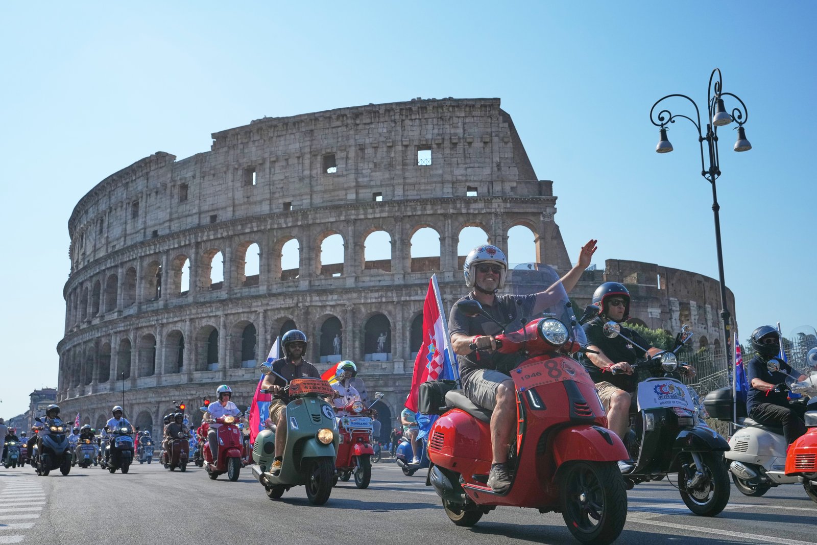អ្នក​ចូល​ចិត្ត Vespa ដើរ​ដង្ហែ​នៅ​មុខ Colosseum ក្នុង​ការ​ប្រារព្ធ​ខួប​លើក​ទី 80 នៃ​ម៉ូតូ Vespa ក្នុង​ទីក្រុង Rome កាលពី​ថ្ងៃ​សៅរ៍ ទី 27 ខែ​មិថុនា ឆ្នាំ 2026។ (រូបថត AP/Alessandra Tarantino)