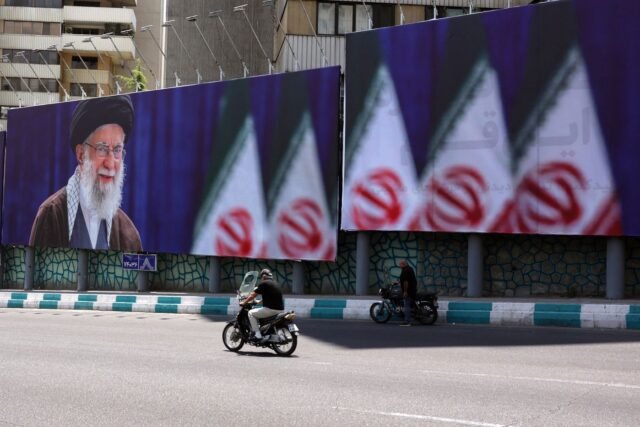1783023472_2479438-des-iraniens-circulent-a-moto-devant-une-affiche-d.jpg