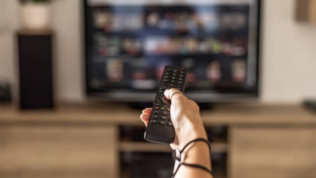 1783836539_0_A-woman-is-holding-a-remote-control-of-a-smart-TV-in-his-hand-In-the-background-you-can-see-the-te.jpeg