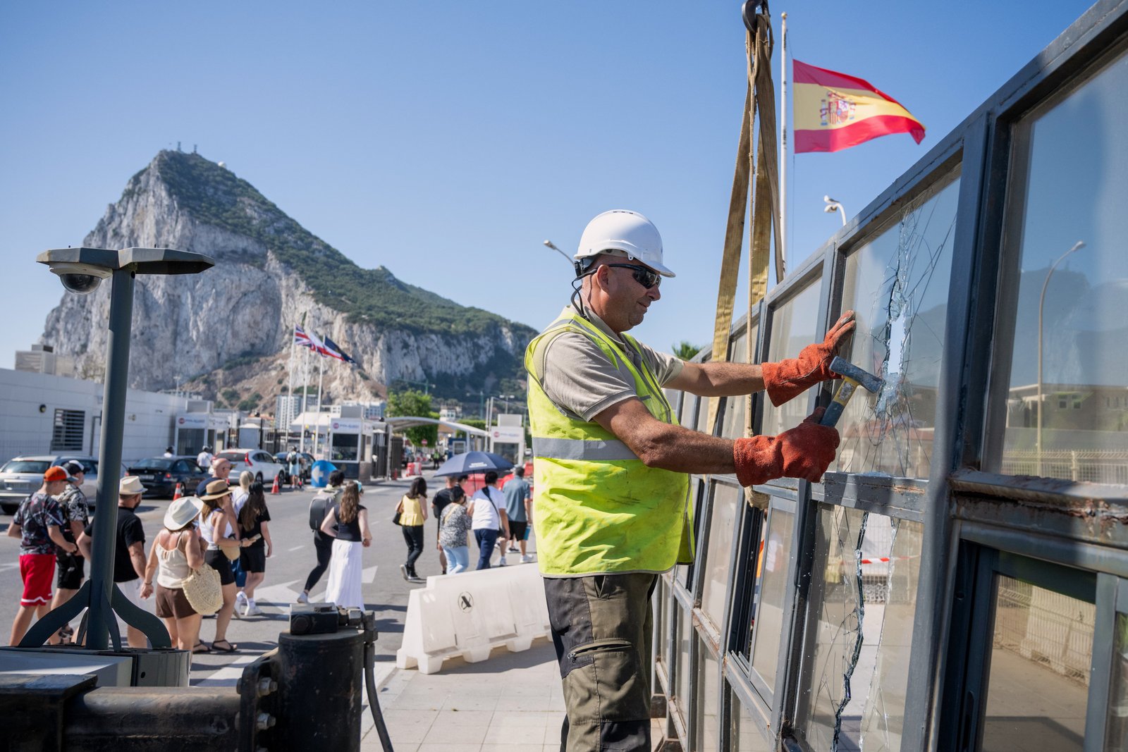 ប្រឆាំងនឹងផ្ទៃខាងក្រោយនៃ Rock of Gibraltar កម្មកររុះរើប៉ុស្តិ៍ត្រួតពិនិត្យព្រំដែនអេស្ប៉ាញដែលបំបែកទឹកដីអង់គ្លេសដែលមានជម្លោះនៅក្រៅប្រទេសពីអេស្ប៉ាញនៅថ្ងៃចន្ទ ទី 6 ខែកក្កដា ឆ្នាំ 2026 នៅ La Línea de la Concepción ប្រទេសអេស្ប៉ាញ។ (រូបថត AP / Marcos Moreno)