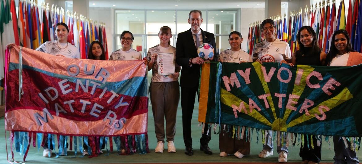 Robb Skinner ឈរជាមួយសមាជិកនៃ Street Child United ក្នុងព្រឹត្តិការណ៍ UN ដោយកាន់បដាដែលអានថា 