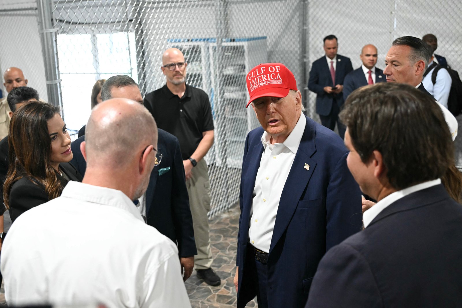 Trump (កណ្តាល) អភិបាលរដ្ឋ Florida លោក Ron DeSantis (ស្តាំ) និងរដ្ឋមន្ត្រីសន្តិសុខមាតុភូមិ Kristi Noem (មិនមានរូបភាព) ធ្វើទស្សនកិច្ចទៅកាន់មជ្ឈមណ្ឌលឃុំឃាំងជនចំណាកស្រុកហៅថា Alligator Alcatraz។