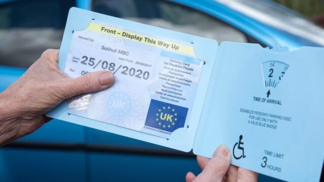 23_Womans-hands-holding-a-Blue-disabled-driver-Badge-parking.jpg