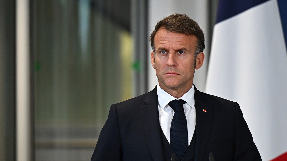 ប្រធានាធិបតីបារាំង Emmanuel Macron ឈរនៅវេទិកាក្នុងឈុតខ្មៅ